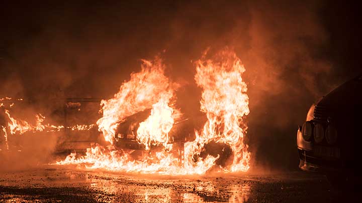 Bilden föreställer bilar som brinner i Sverige.
