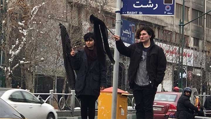 Två kvinnor i Teheran viftar med sina slöjor.